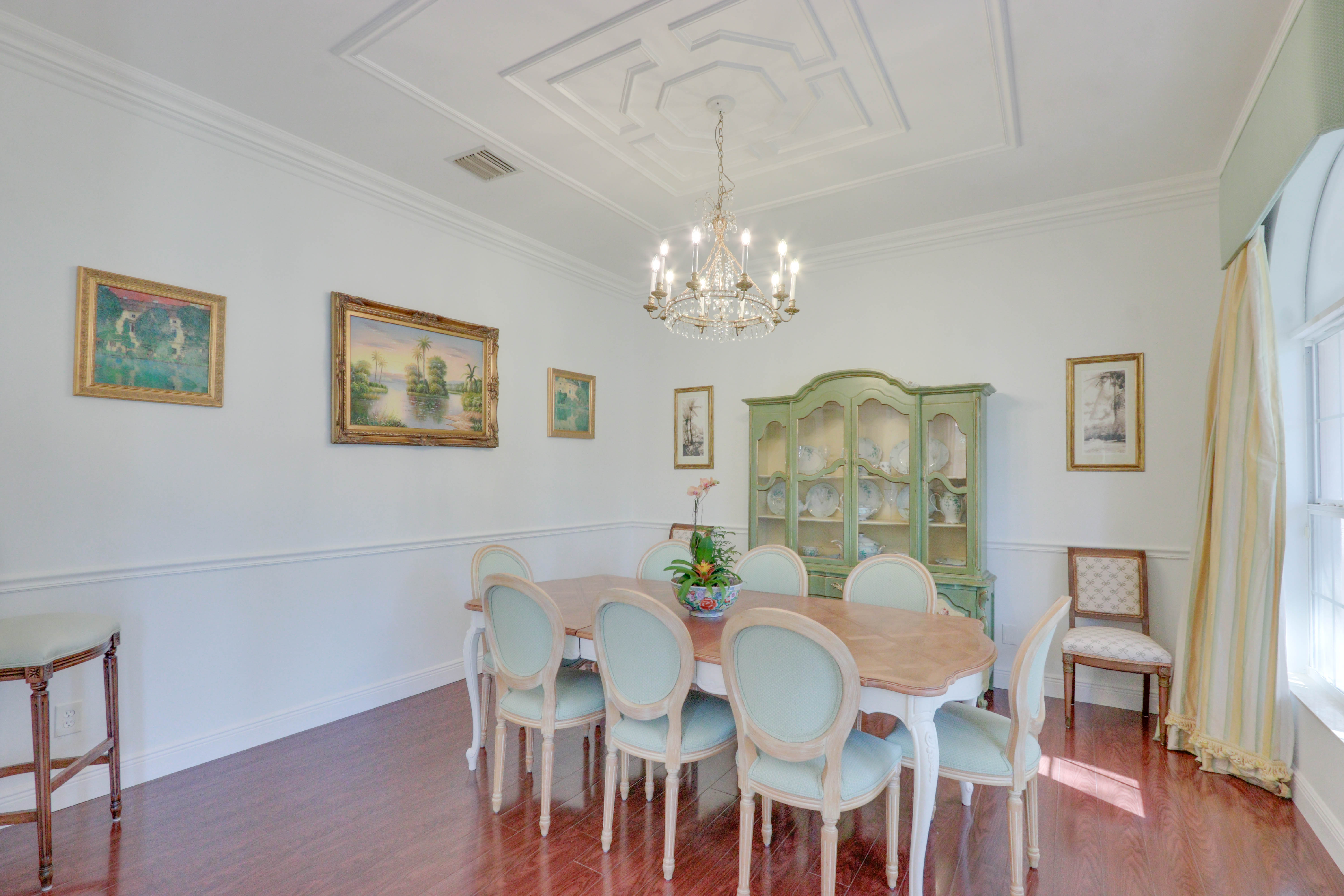 Formal dining salon at Maison Sarti with long table place settings and a sage green hutch
