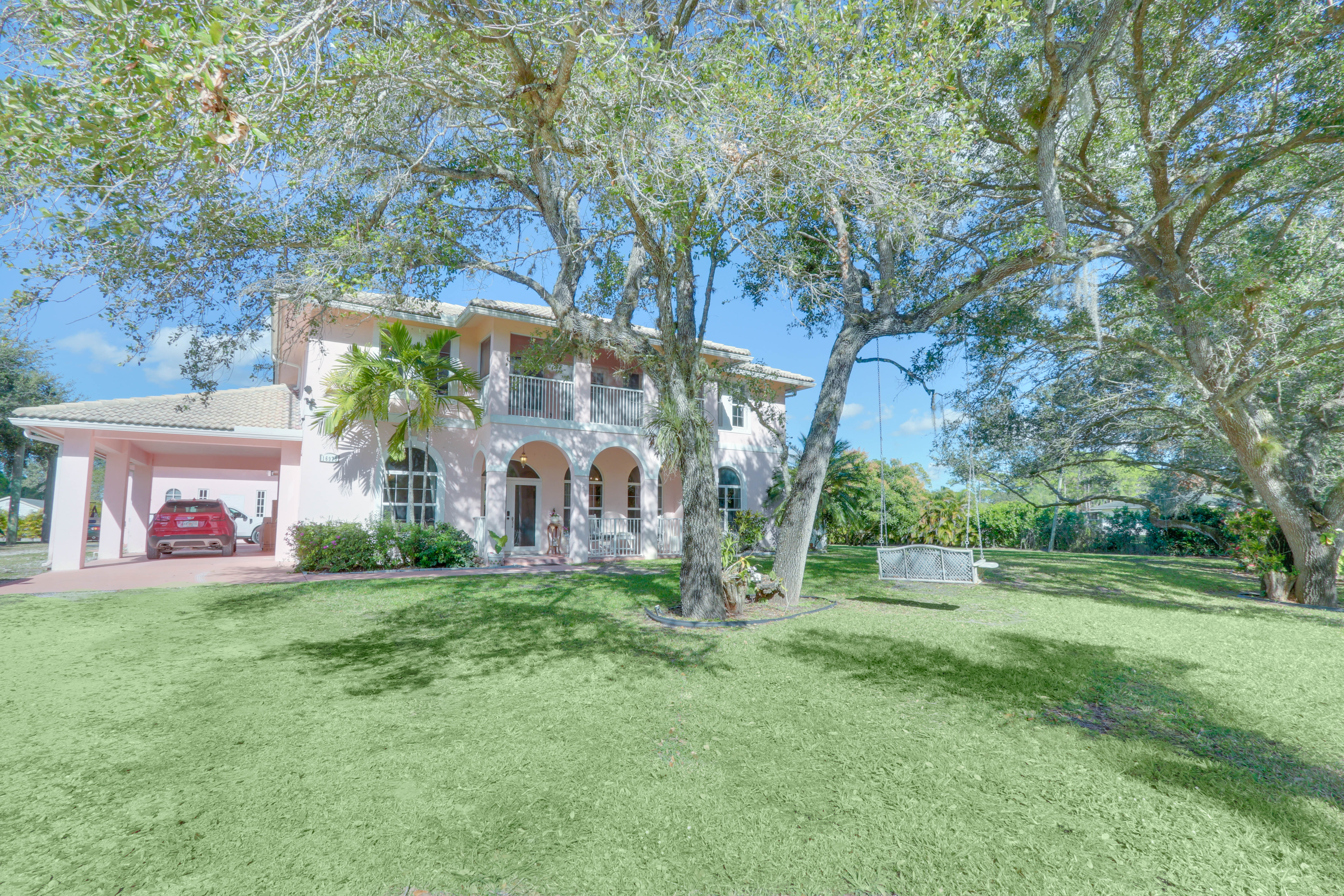 Soft pink Mediterranean exterior of Maison Sarti with lawn and mature trees